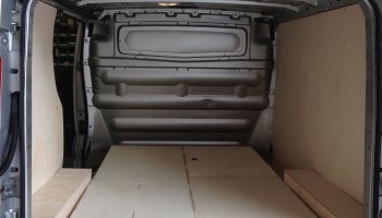 Ply lining and floor drawers, with one open drawer, in the back of a van